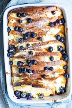 baked french toast with blueberries and powdered sugar in a casserole dish