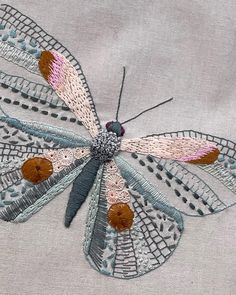 a close up of a dragonfly embroidered onto a piece of cloth with stitches on it