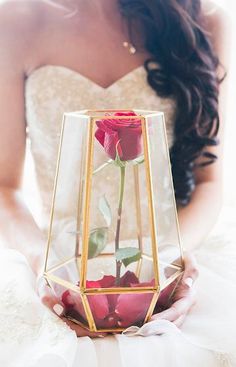 a woman holding a rose in a glass vase