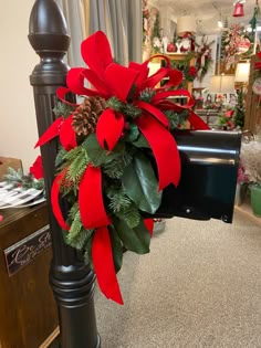 a mailbox decorated with red and green christmas wreaths, pine cones and greenery