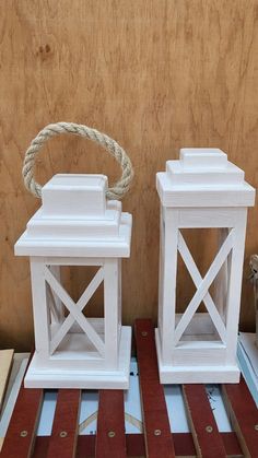 two white lanterns sitting on top of wooden boards