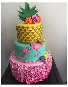 a three tiered cake decorated with pink, blue and yellow frosting flamingos