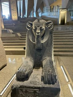 a statue of an egyptian god with his hands in his mouth, sitting on a stone block