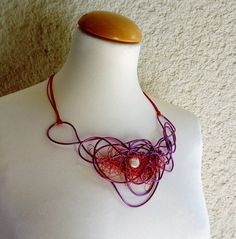 a white mannequin with a red and purple necklace on it