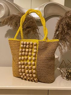 two woven bags sitting on top of a white shelf next to dried plants and vases