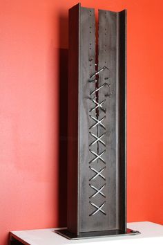 a tall metal object sitting on top of a white table next to a red wall