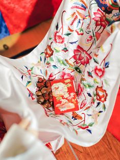 a white cloth with red and blue flowers on it sitting on a wooden floor next to a table