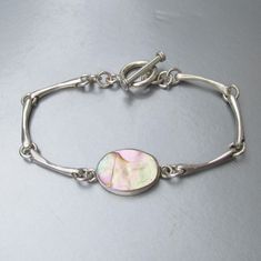 This early 2000s vintage solid 950 silver (more silver content than sterling which is 925) heavy bar link toggle bracelet has one 1" long oval center link of pale blue, tan, and white iridescent abalone shell.  The sides have three of the slightly curved bar links and it ends with the round toggle clasp.  It measures 7 3/4" long which is a longer length than average so it is a perfect unisex bracelet for a gift.  It is signed, "Green River Silver Co. 950" and is in excellent, like-new condition Curved Bar, Green River, Dope Jewelry, 2000s Vintage, Toggle Bracelet, Funky Jewelry, Unisex Bracelets, Abalone Shell, Toggle Clasp