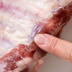 a person is holding up some meat in their left hand and touching it with the other hand