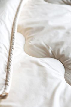 an unmade bed with white sheets and pillows