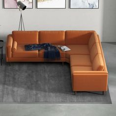 an orange sectional sofa in a living room with three pictures on the wall behind it