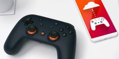 a black controller next to an iphone on a white table with a red and orange background