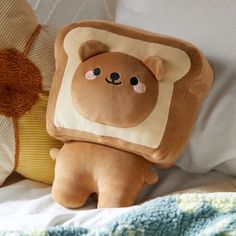 a brown teddy bear sitting on top of a bed next to a pillow and blanket