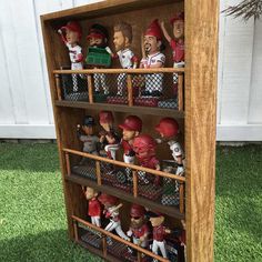 a wooden shelf filled with baseball figurines on top of grass