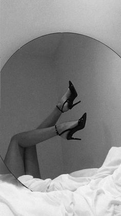 a woman's legs in high heels are reflected in a mirror on a bed