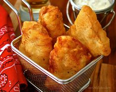 there are some fried food in a basket on the table next to a glass of beer