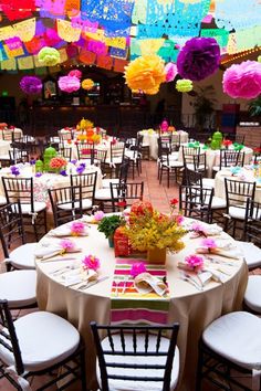 tables and chairs are set up with colorful paper flowers on them for a party or celebration