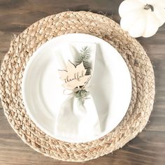 a place setting with white pumpkins and leaves on the plate, along with a thank you napkin