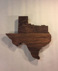 a wooden state shaped like the shape of texas on a white wall with wood grain