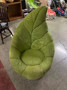 a green bean bag chair sitting on the floor in a room with other chairs and bookshelves