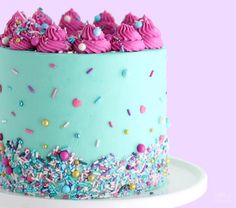 a blue cake with pink frosting and sprinkles on it's side