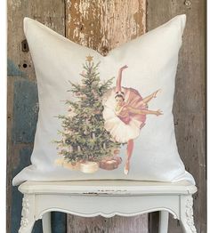 a white chair with a pillow on it and a christmas tree in front of it