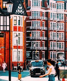 a woman walking down the street with an umbrella over her head and cars parked in front of buildings