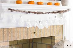 a fireplace decorated for halloween with white ghost decorations and pumpkins on the mantel