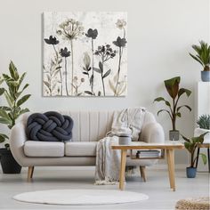 a living room with white furniture and plants on the wall, including an art piece