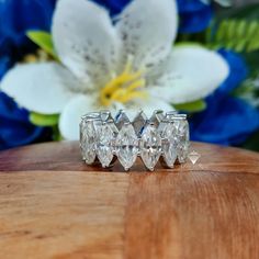 three diamond rings sitting on top of a wooden table next to a white and blue flower