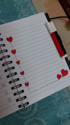 a notepad with hearts drawn on it and a pen resting on the page next to it