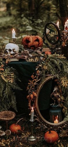 a table topped with lots of fake pumpkins next to candles and other decorations in the woods