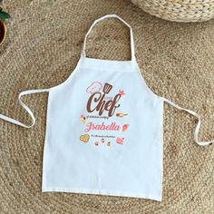 an apron with the word chef on it sitting next to a bowl of fruit and strawberries