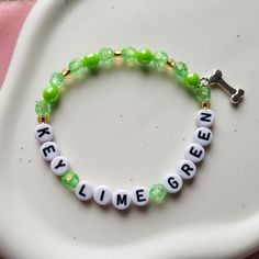 "Key Lime Green" bracelet, on a stretch chord - referencing The Last Great American Dynasty.  If there are any designs you are looking for but can't find, send me a message and I can create it for you.  **Due to the nature of the material of the beads, I recommend keeping your bracelets dry and away from water or chemicals when possible. The white and light color beads will show wear and tear/dirt quicker than the darker colors. Keeping the bracelets dry and away from lotions, chemicals, dyed garments, etc. will help keep them looking new for much longer.                                                                                                                  -Alyssa from LyssieBCreations The Last Great American Dynasty Bracelet, Custom Name Green Bracelet For Friendship, Green Custom Name Friendship Bracelet, Novelty Green Beaded Bracelets, Customized Green Bracelets As Gift, Custom Name Green Jewelry For Friendship, Green Novelty Bracelets With Round Beads, Customizable Green Bracelet Jewelry, Customized Green Name Bracelet For Friendship