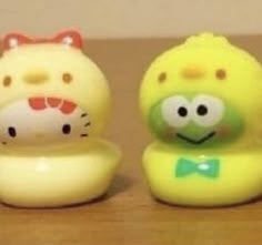 three yellow rubber toy animals sitting on top of a wooden table next to each other