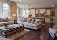 a living room filled with furniture next to a kitchen and an open concept floor plan