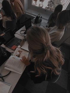 a group of people sitting around a table with laptops and notebooks on it