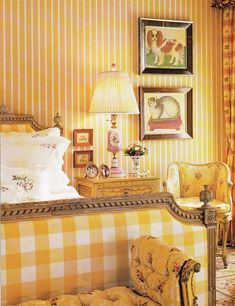 a bed room with a neatly made bed next to a lamp and pictures on the wall