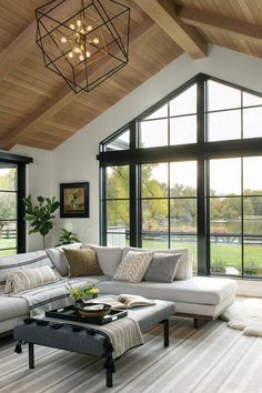 a living room filled with lots of furniture next to large windows on top of a wooden ceiling