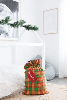 a bag sitting on top of a bed next to a white pillow and christmas tree