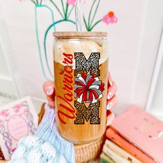 a person holding a cup with a straw in it next to books and other items