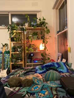 a room with plants and blankets on the floor