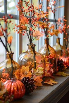 vases filled with autumn leaves and berries sit on a window sill