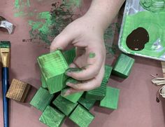 a person is making wooden blocks with green paint