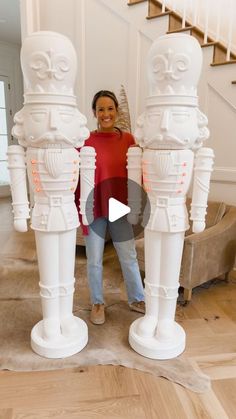 a woman standing next to three white statues in front of a stair case and stairs