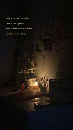 a dark room with a lit candle and some books on the shelf next to it