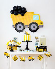 a table topped with black and yellow desserts next to a construction truck wall hanging on the wall