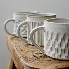 three white coffee cups sitting on top of a wooden table