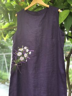 a purple dress with daisies on it hanging from a tree