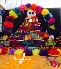 a decorated table with candles and decorations for a mexican day of the dead party on display